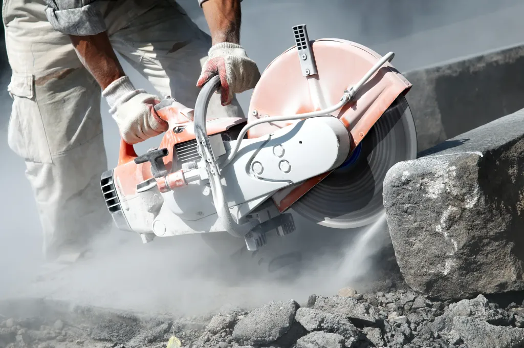 Worker cutting concrete with a power saw on a jobsite